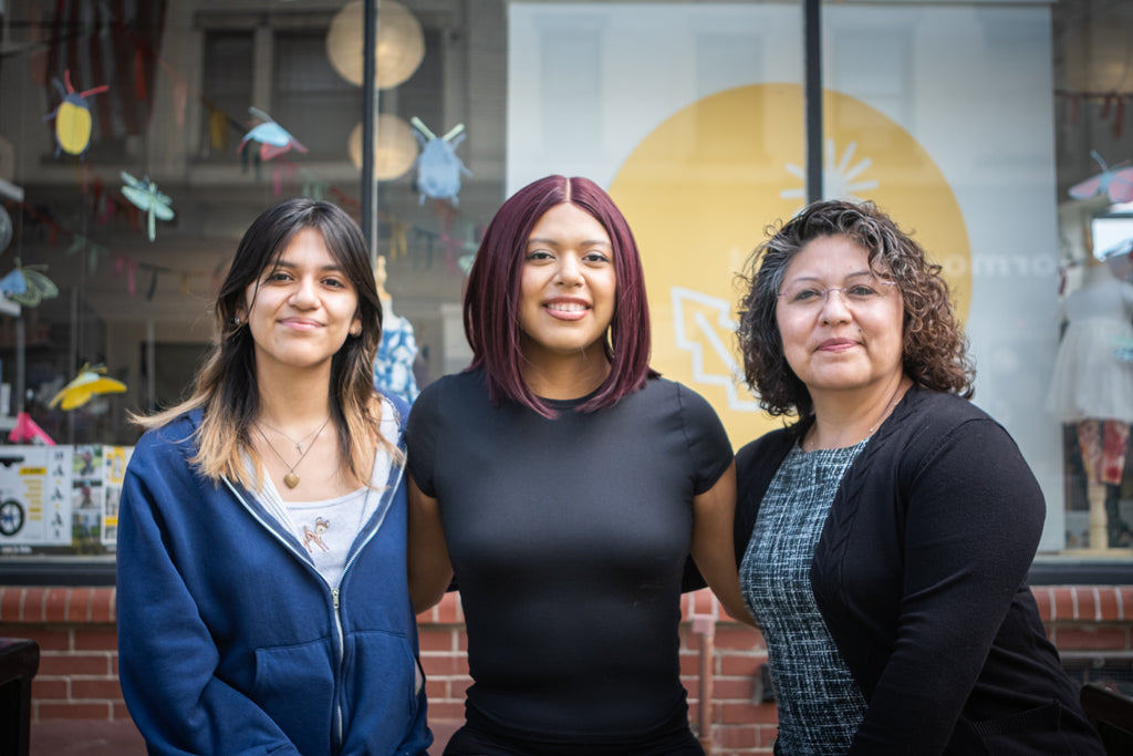 A trio of women stand in front of a store front. The woman on the right has curly hair and would like to know about the best curly hair products. 